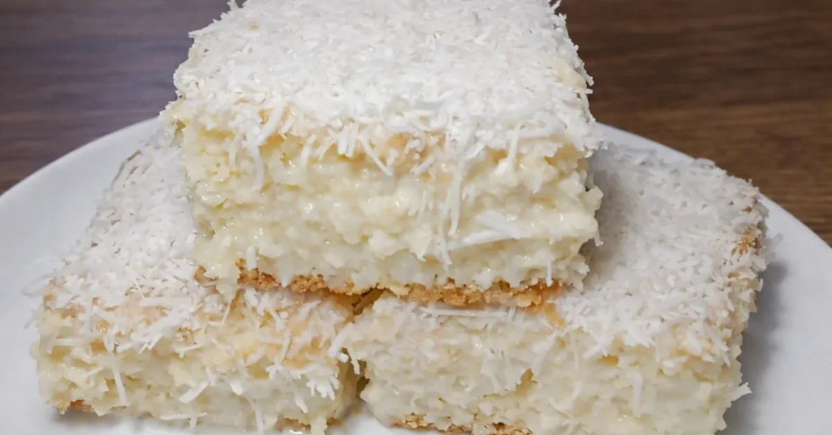 Bolo gelado de coco cremoso com cobertura de coco, apresentado em pedaços para venda individual